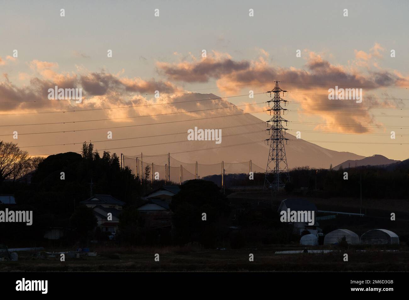 Mount Fuji at sunset behind electricity pylons and houses in rural Kanagawa, Japan. Stock Photo