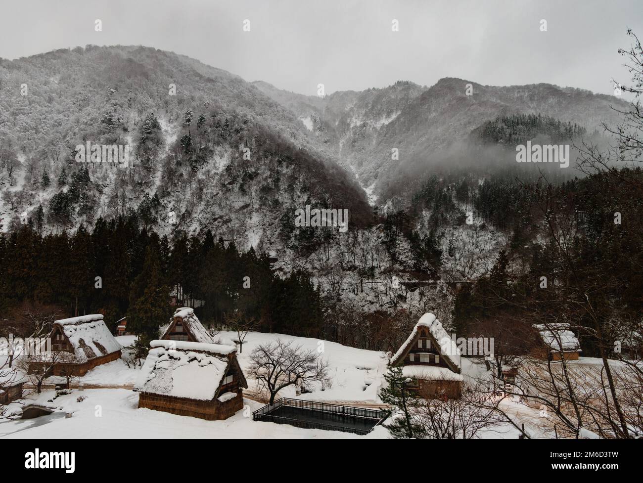 Traditional Japanese village and misty snow covered mountains in winter Stock Photo