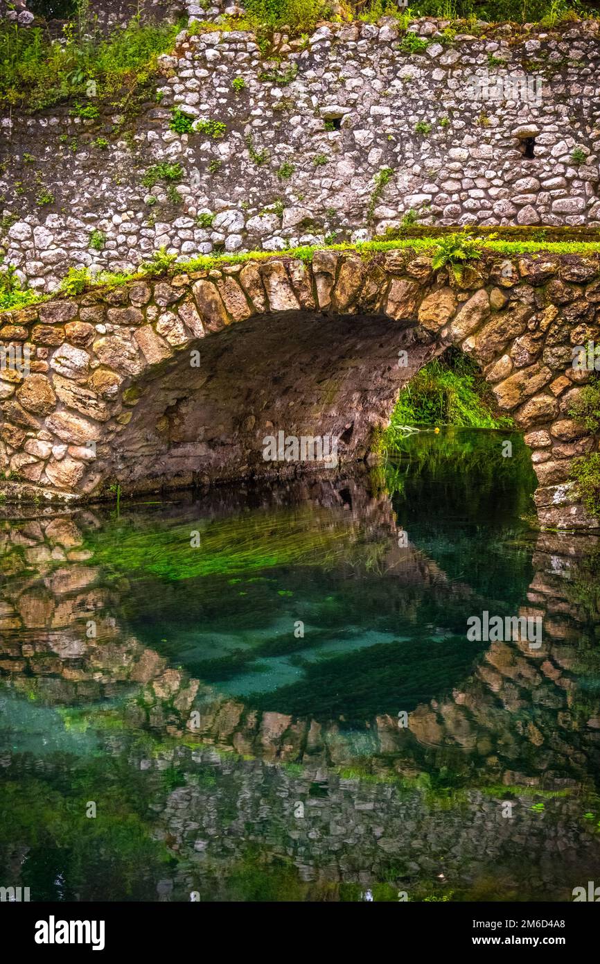 Round stone bridge reflected in river water vertical background Stock Photo