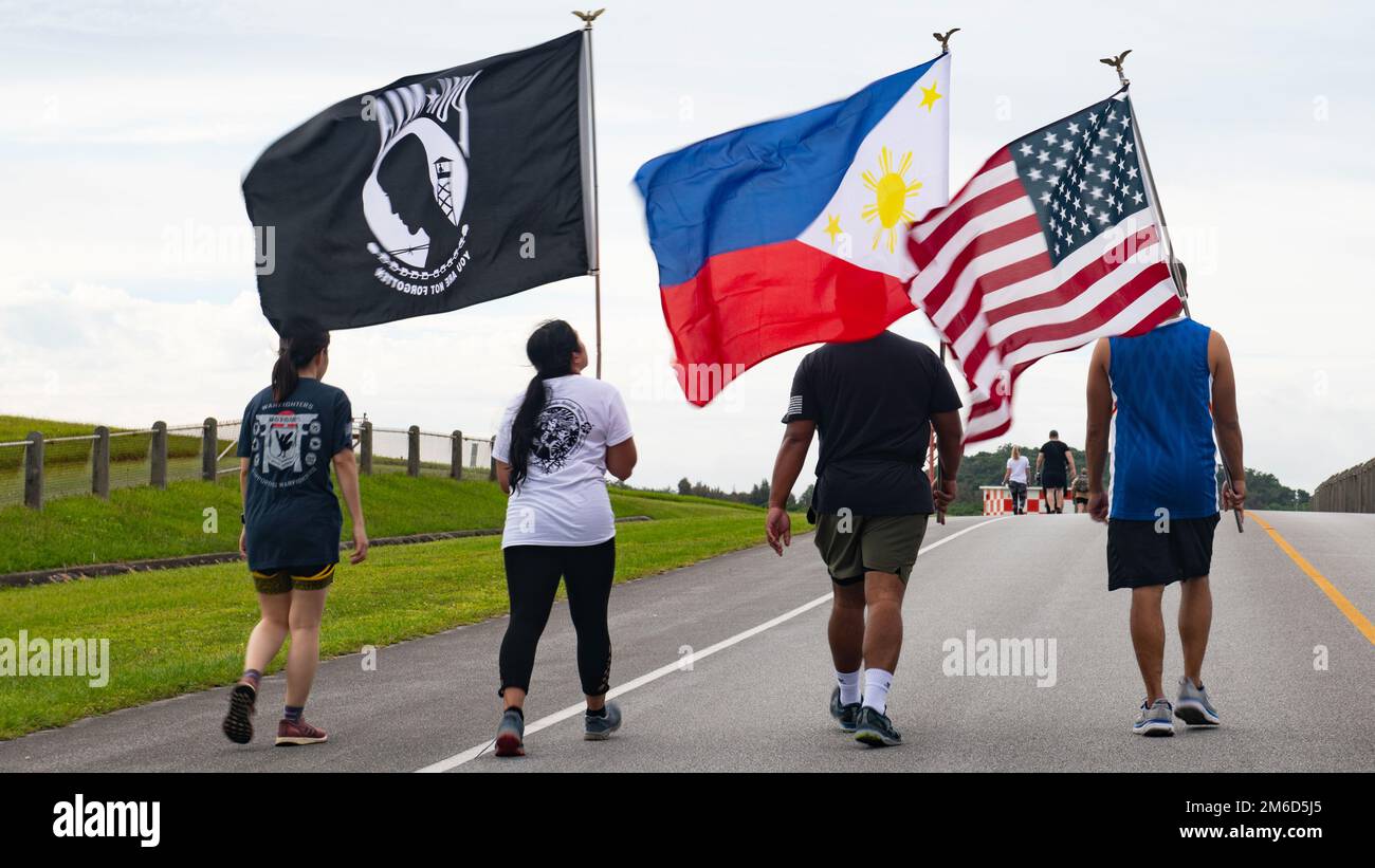 Participants carry flags during the 9th Annual Memorial for the Bataan Death March  at Kadena Air Base, Japan, April 23, 2022. The event commemorated casualties and survivors from the 1942 Bataan Death March, during which approximately 76,000 Filipino and American service members endured a nearly 70-mile march during a prison transfer. Stock Photo