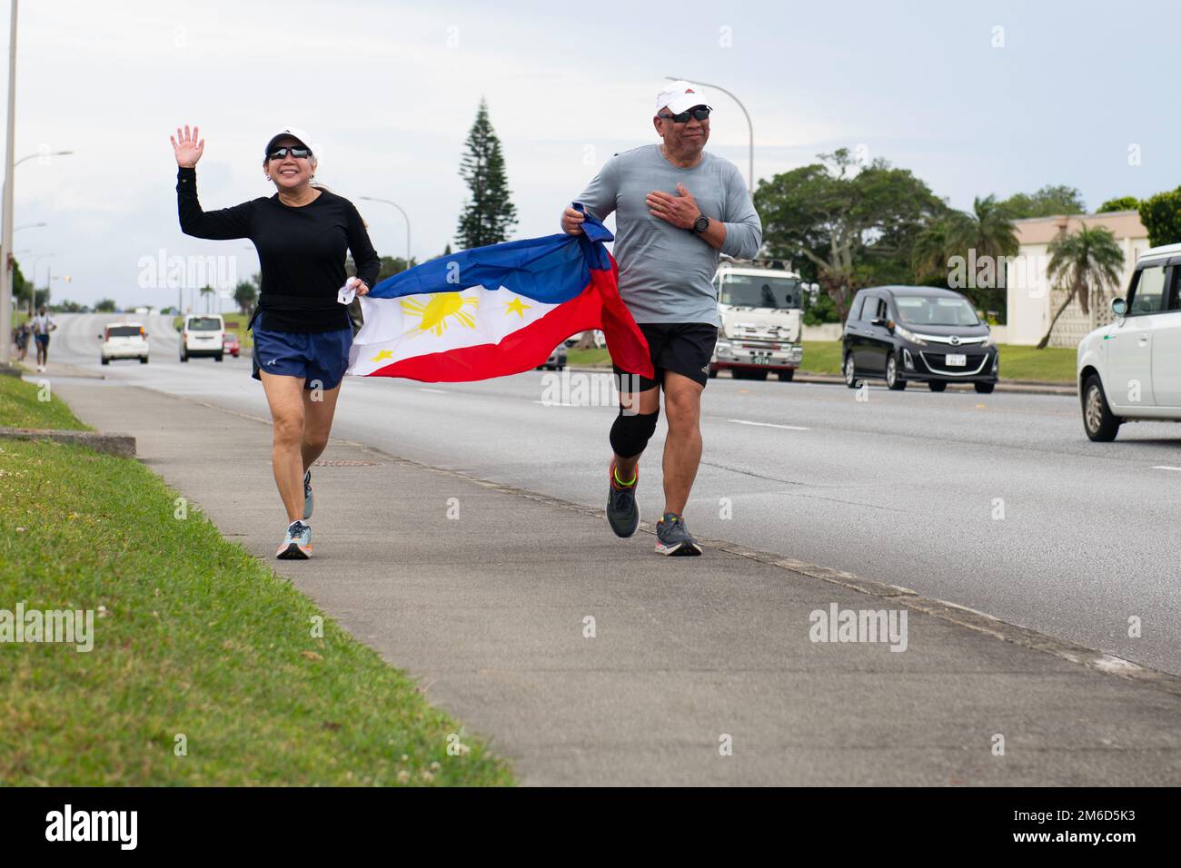 Runners cross the finish line displaying the Flag of the Philippines at the 9th Annual Memorial for the Bataan Death March at Kadena Air Base, Japan, April 23, 2022. The 8.5-mile run/ruck/walk was held to commemorate the American and Filipino servicemen who were marched nearly 70 miles to prison camps after surrendering at the Bataan Peninsula in April of 1942. Stock Photo