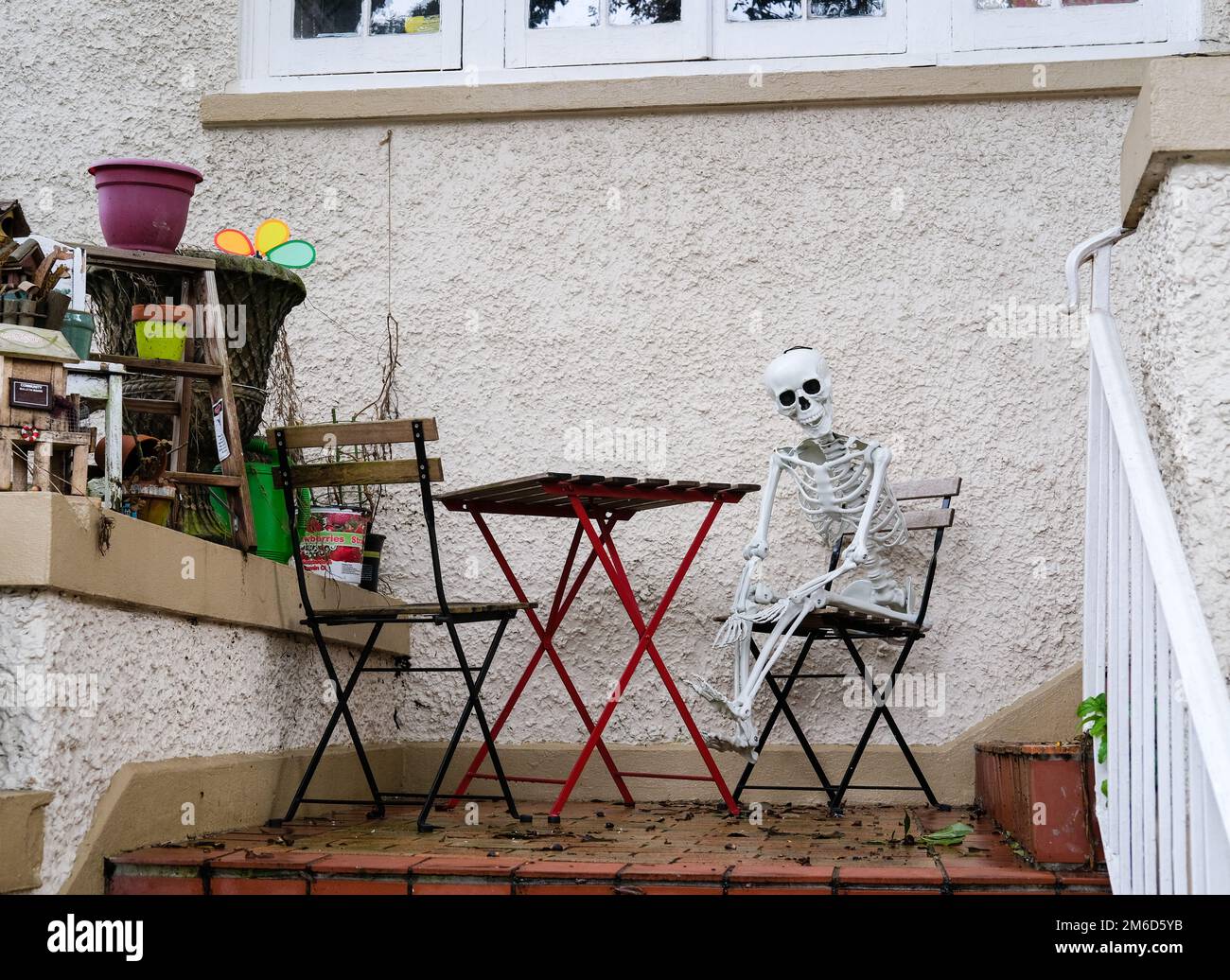 NEW ORLEANS, LA, USA - JANUARY 2, 2023: Skeleton (Halloween decoration) sitting in a folding chair next to a folding table on a front porch Stock Photo