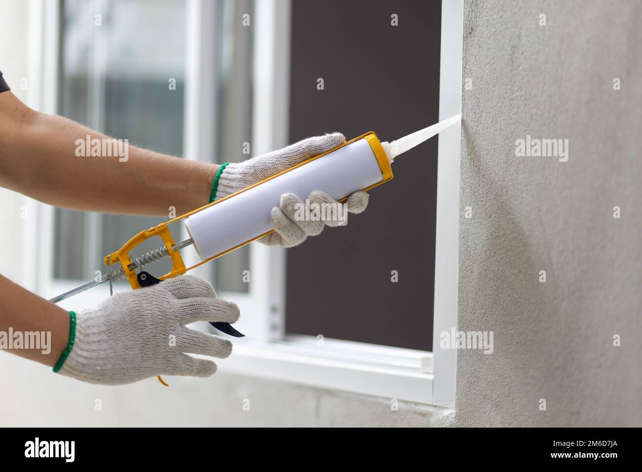 Construction worker using silicone sealant caulk the outside window