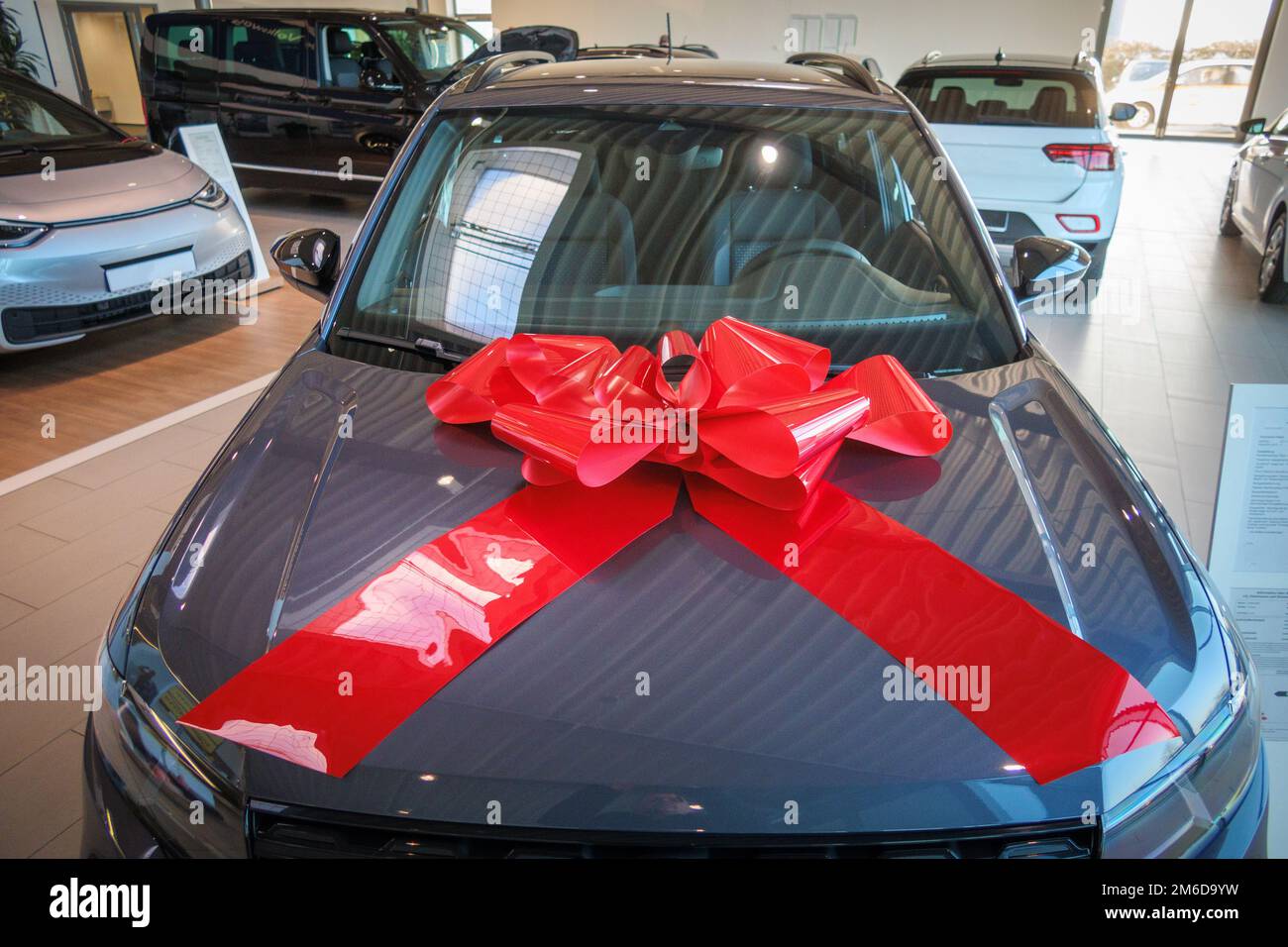 a big red ribbon is on the hood of a new car Stock Photo - Alamy