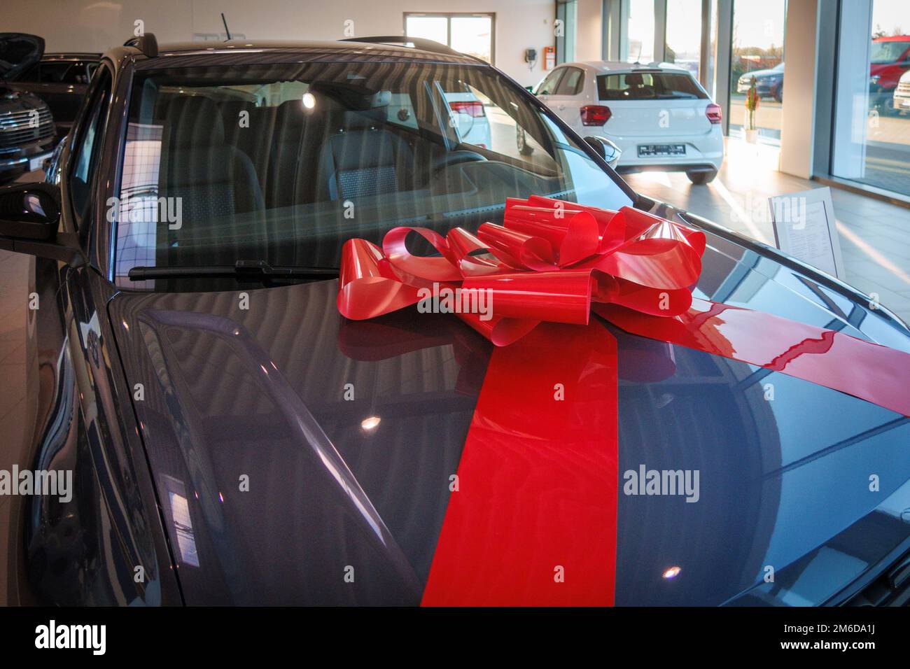 a big red ribbon is on the hood of a new car Stock Photo - Alamy