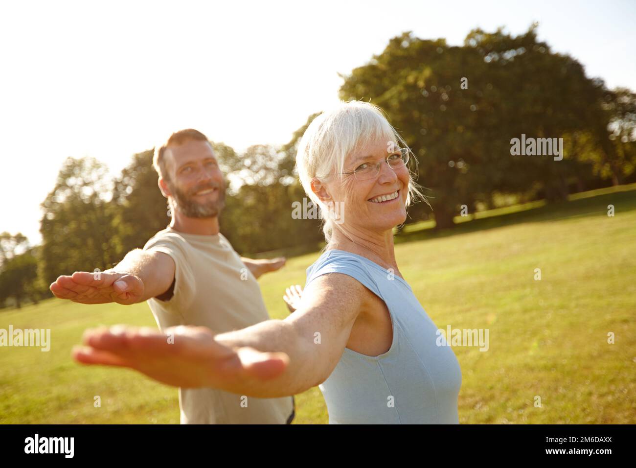 This is how we keep ourselves feeling young. Portrait of a happy mature couple doing yoga together outdoors. Stock Photo