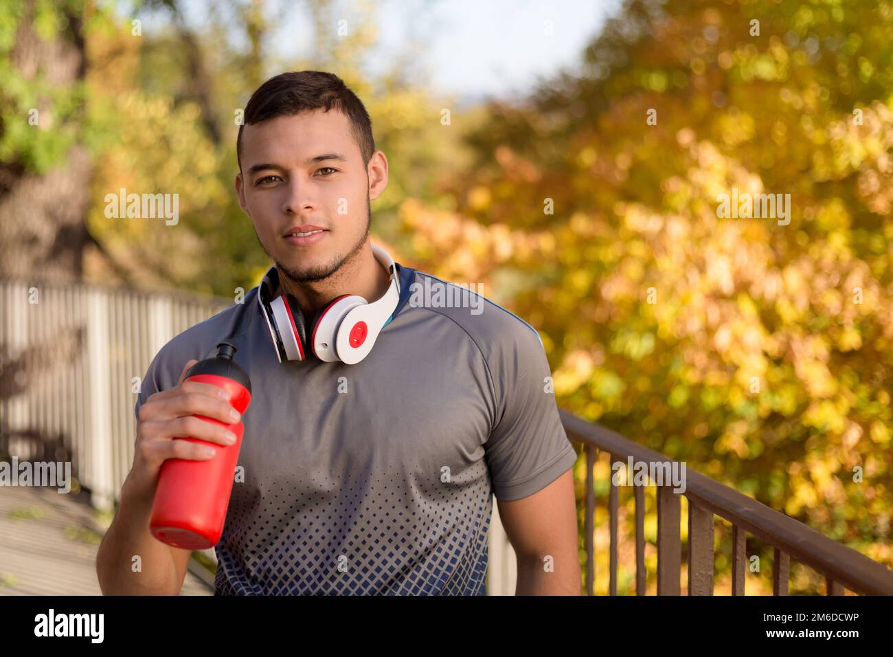 Young latin man drinking water runner running jogging autumn fall copyspace copy space Stock Photo