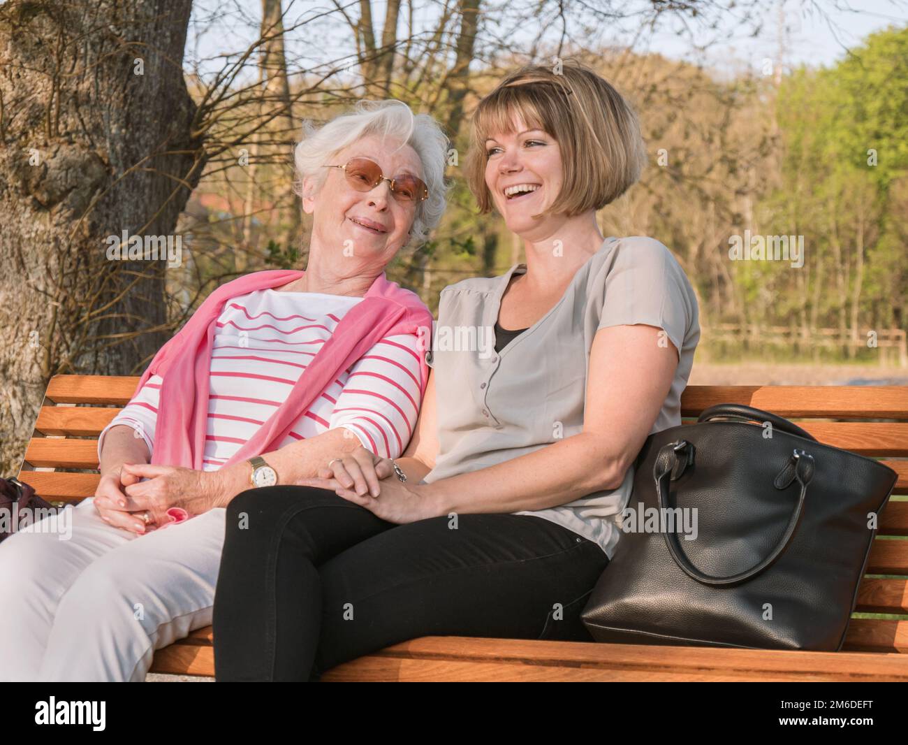 Senior lady an daughter smiling while sitting in the park Stock Photo