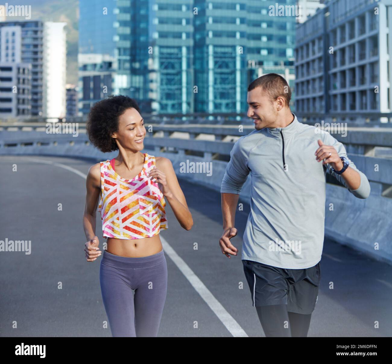 Think you can keep up. two friends jogging together through the city streets. Stock Photo