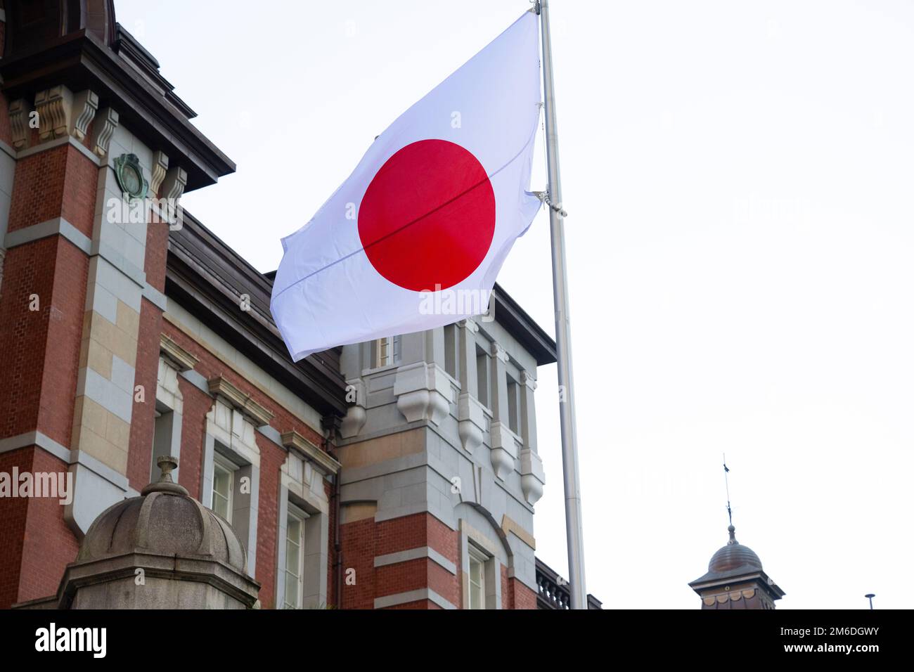 Tokyo, Japan. 3rd Jan, 2023. Japanese flags (Hinomaru) fly outside Tokyo Station (æ±äº¬é§…), the central intercity station on the Japanese Shinkansen bullet train high speed rail network for JR East and JR Central, in the Marunouchi business district near the Imperial Palace grounds with tourists, commuters, business travelers and holiday travelers alike passing through.Japanese Yen (JPY) steward, Bank of Japan Governor Haruhiko Kuroda doubled the interest cap on 10-year bonds on a stimulus program to increase the value of the Japanese Yen on foreign currency exchanges. Finance, economy, Stock Photo