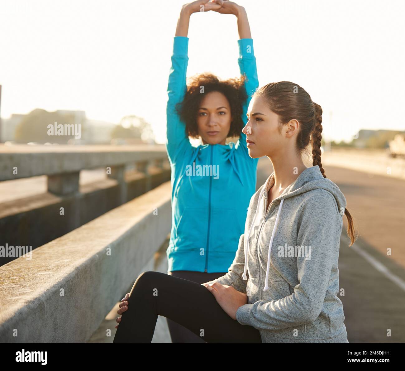 Limbering up for a run. two friends stretching together before a run through the city streets. Stock Photo