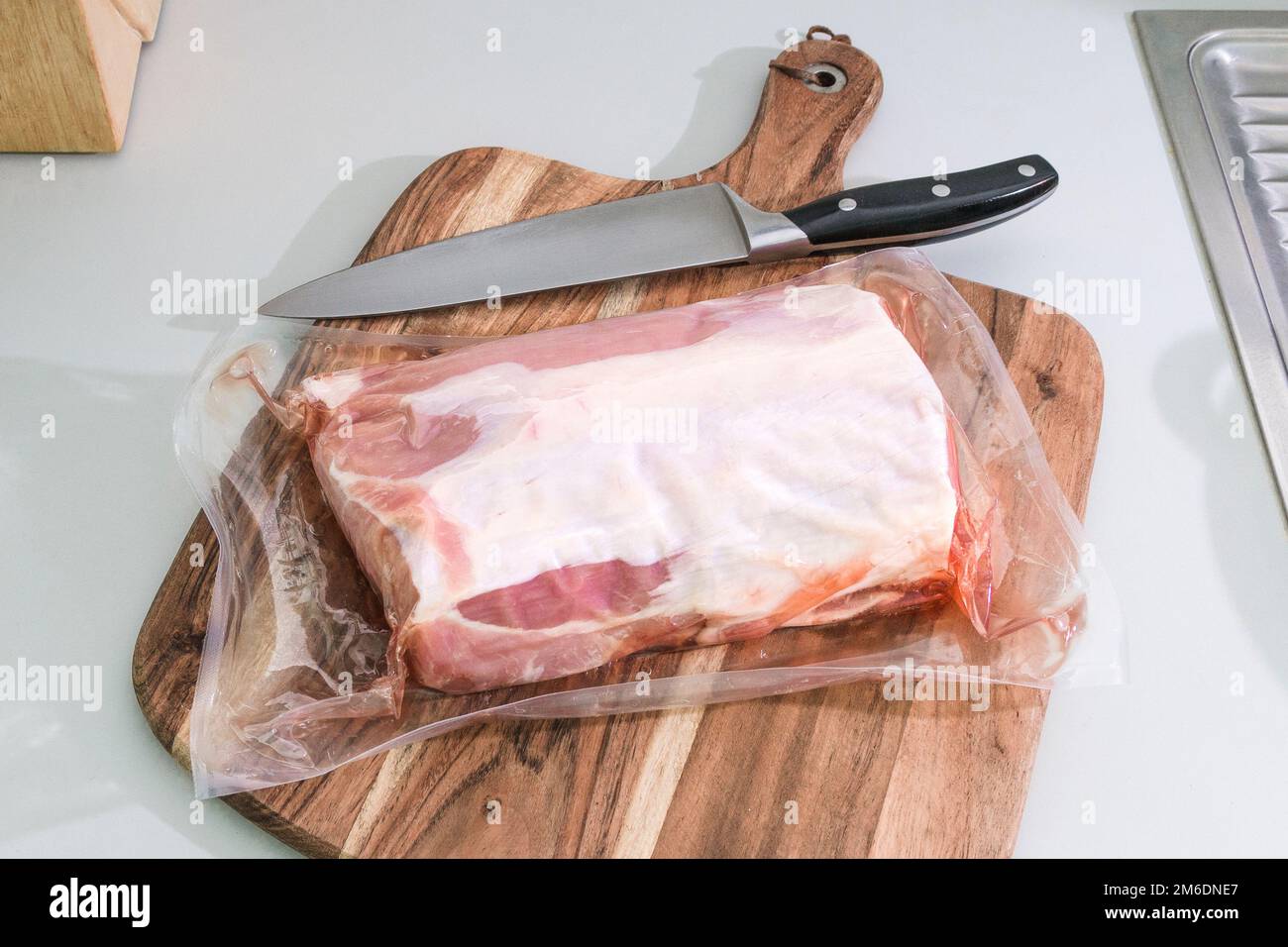 A piece of vacuumpacked pork tenderloin on a cutting board in the
