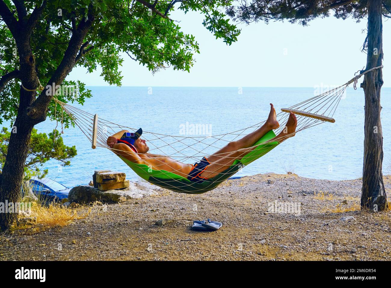 A young man is resting in a hammock on the beach . Stock Photo