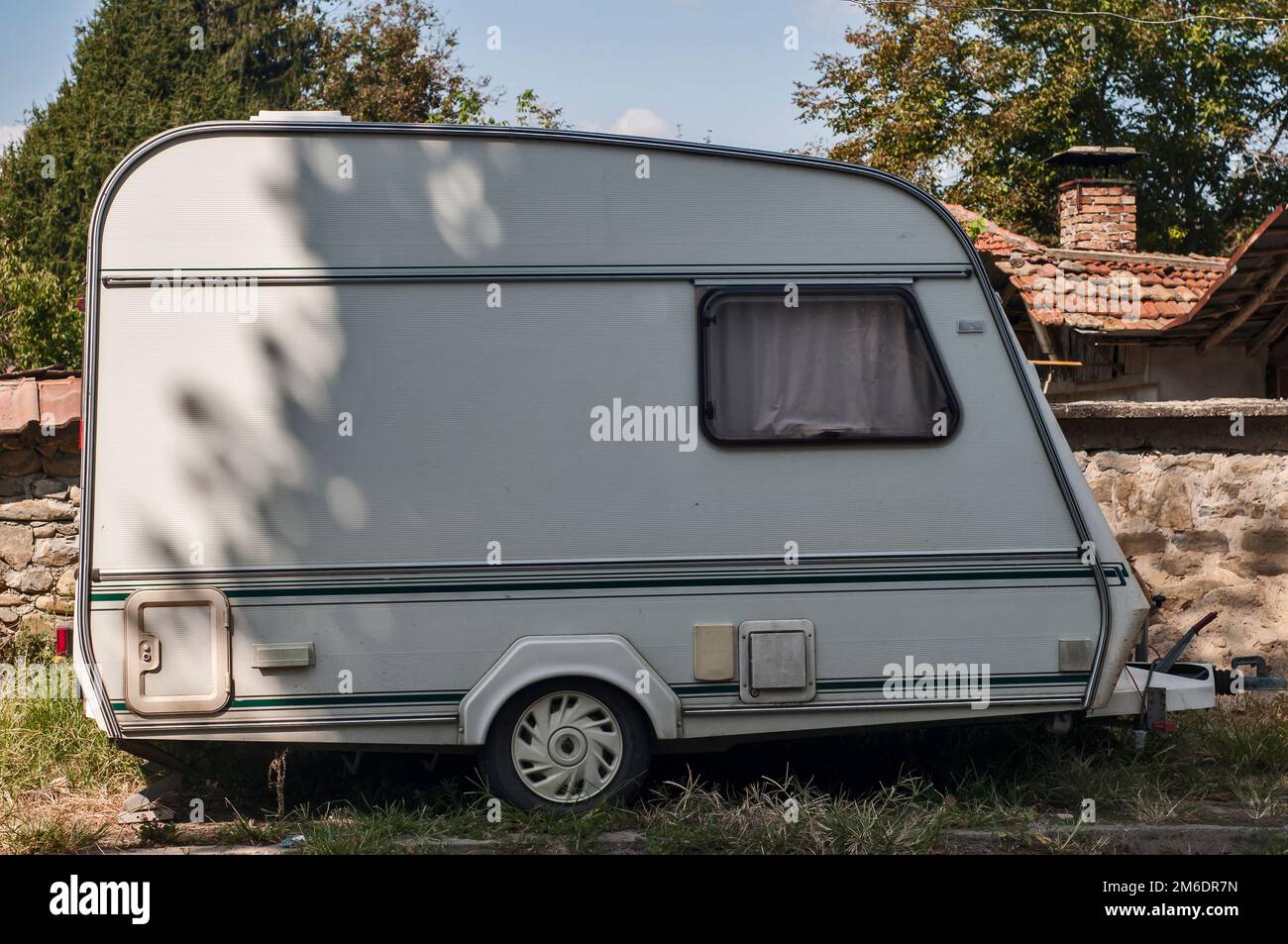 Old vintage caravan side view closeup at country house in sunny day Stock Photo