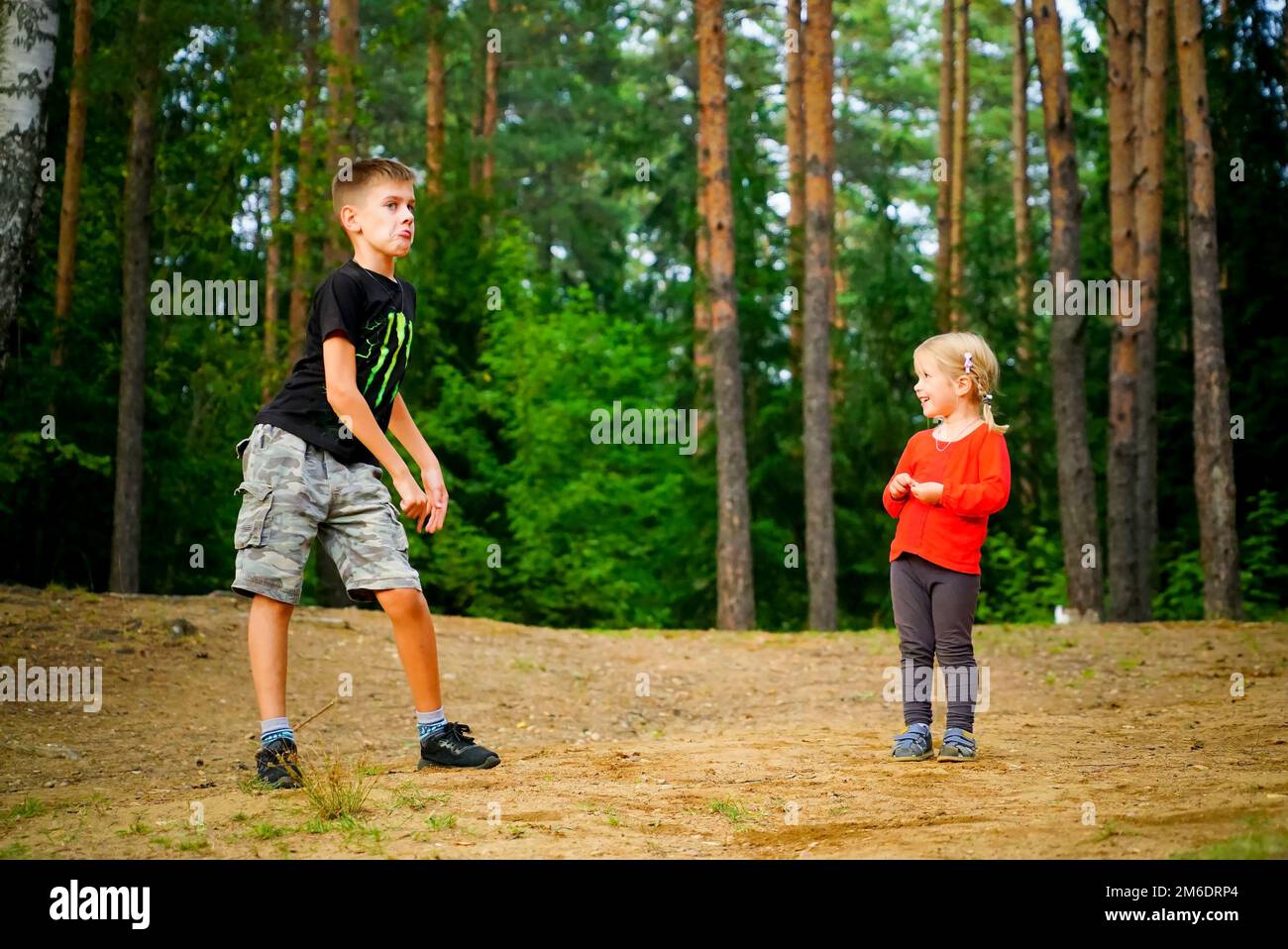 A boy and a girl are dancing merrily in a clearing in the forest . Stock Photo