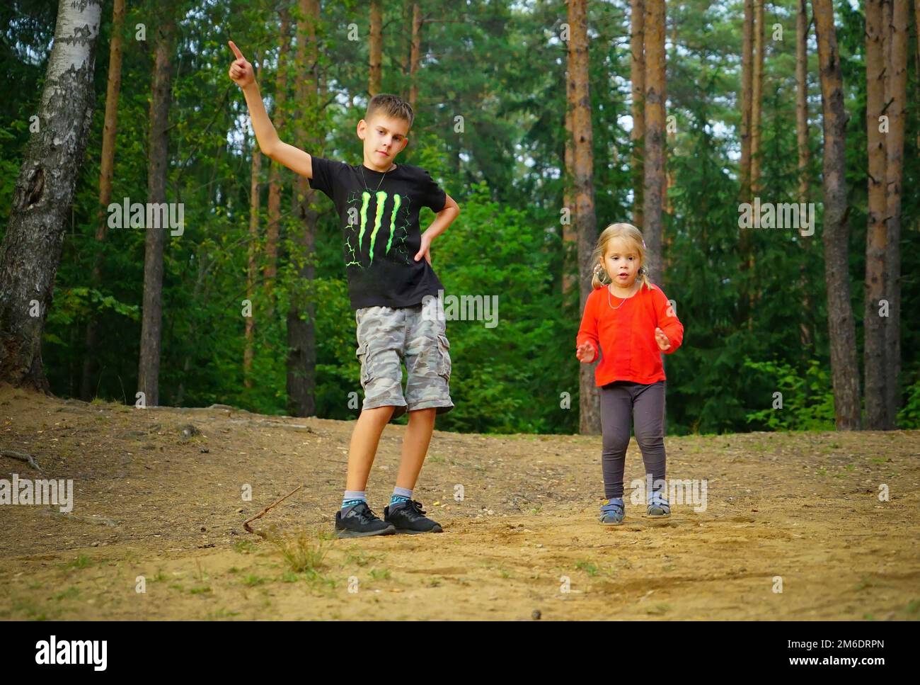A boy and a girl are dancing merrily in a clearing in the forest . Stock Photo