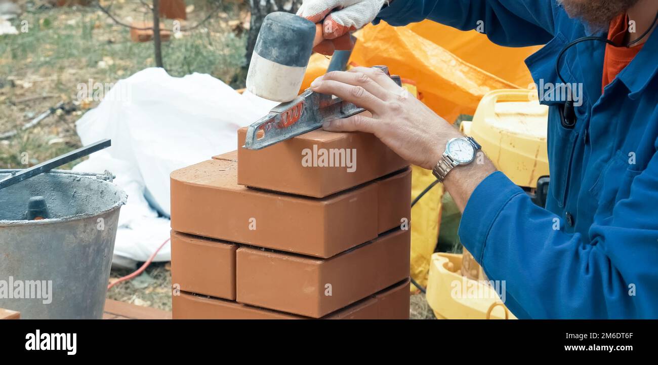 A man builds a brick wall. Brick put on the solution. Construction of brick house Stock Photo