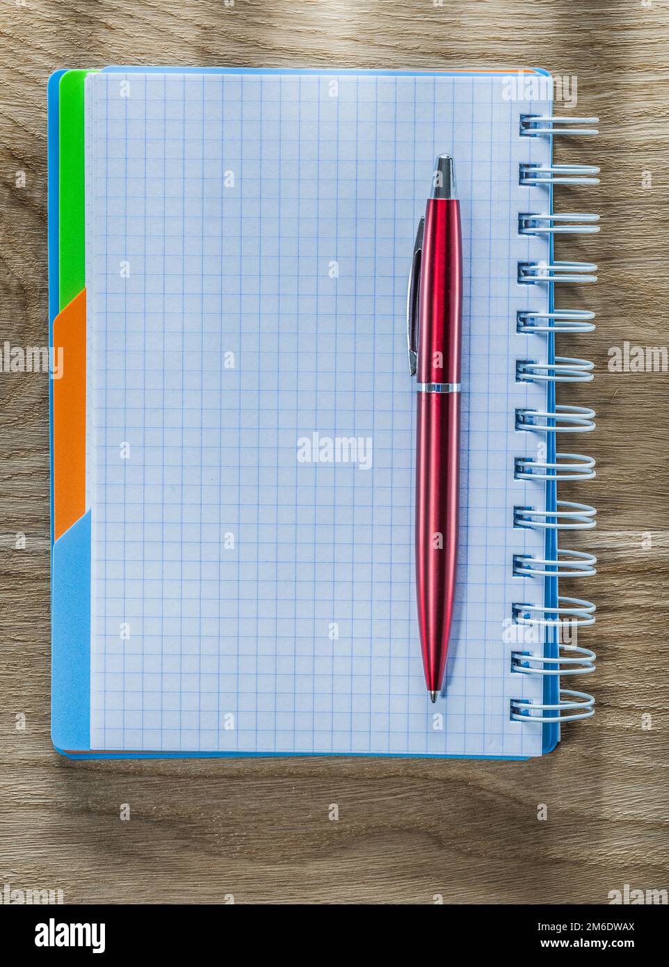 Checked spiral notebook pen on wood board. Stock Photo
