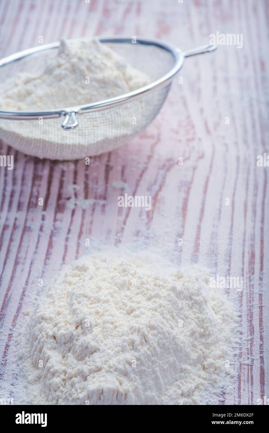 flour in sieve on vintage wooden board food and drink concept Stock