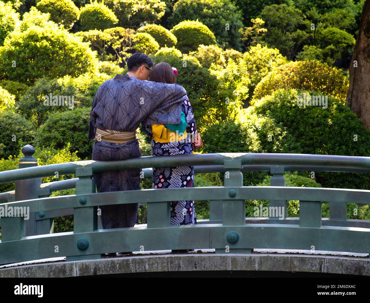 A young couple wearing kimonos cuddling on a bridge Stock Photo