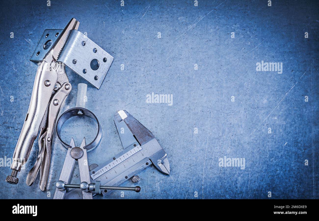 Metal lock jaw pliers slide caliper perforated mounting brackets construction pair of compasses on metallic background. Stock Photo