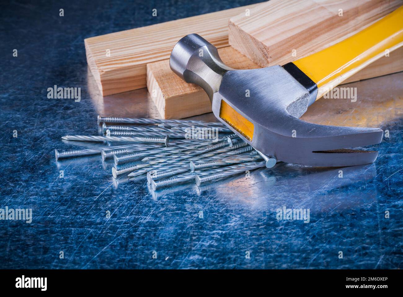 Metal nails claw hammer and wooden studs on scratched metallic