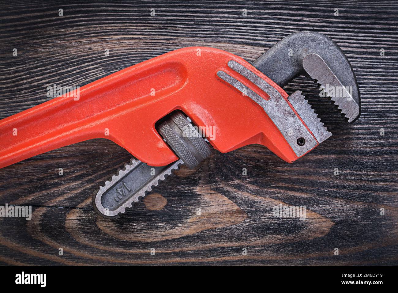 Red metal pipe wrench on wooden board plumbing concept. Stock Photo