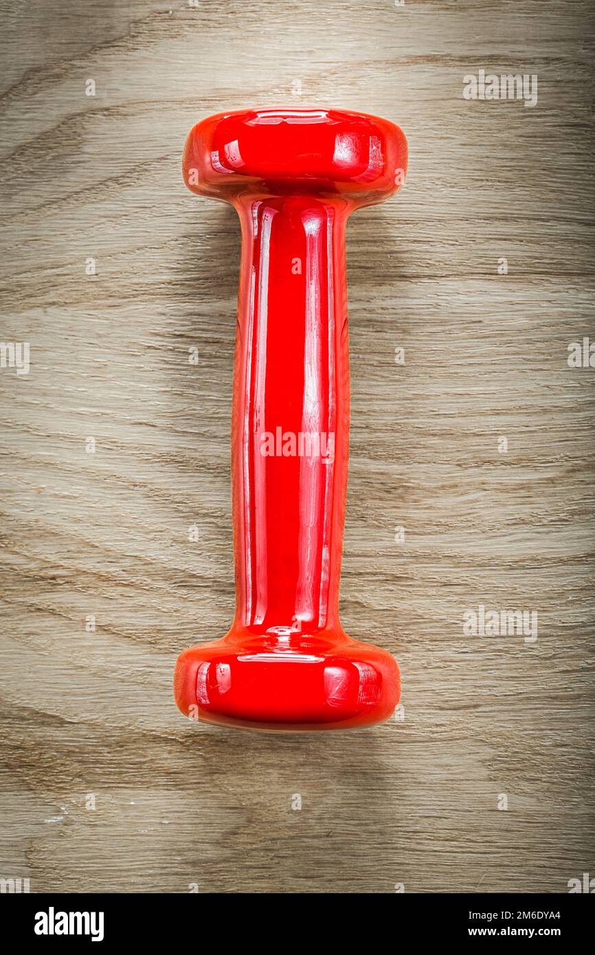 Single red dumb-bell on wood board sports training concept. Stock Photo