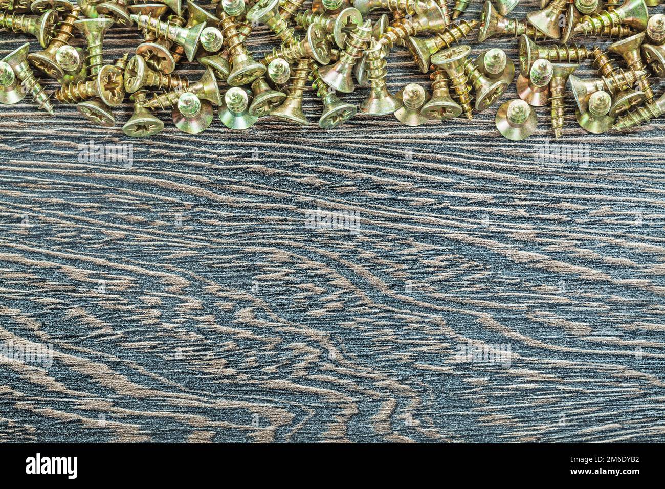 Stack of screws on wooden board. Stock Photo