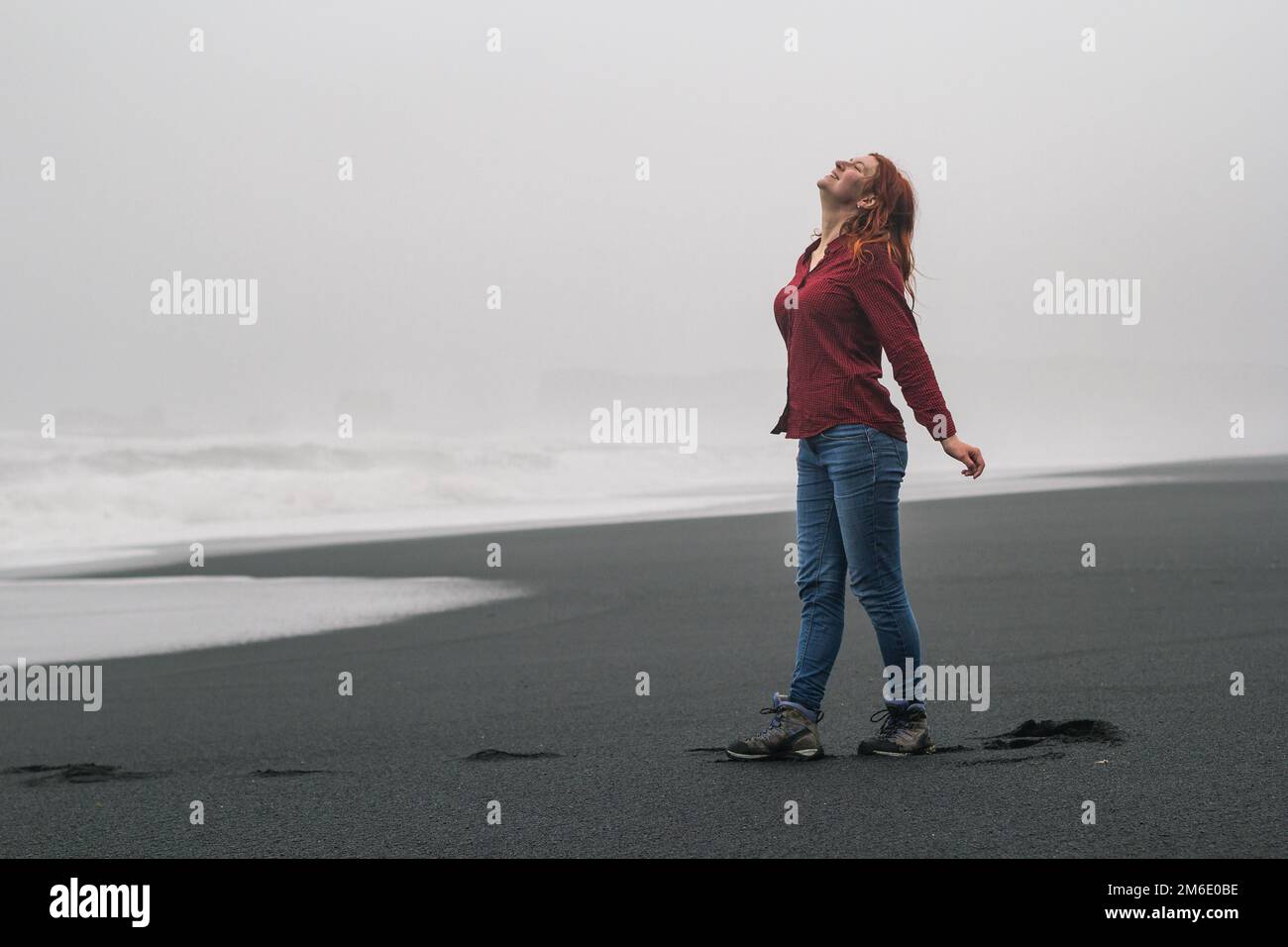 Joyful woman on empty black beach scenic photography Stock Photo