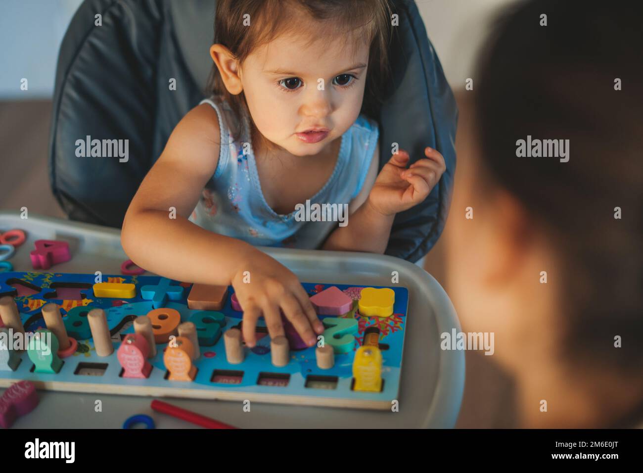 Cute baby playing with colorful wooden game with letters and numbers
