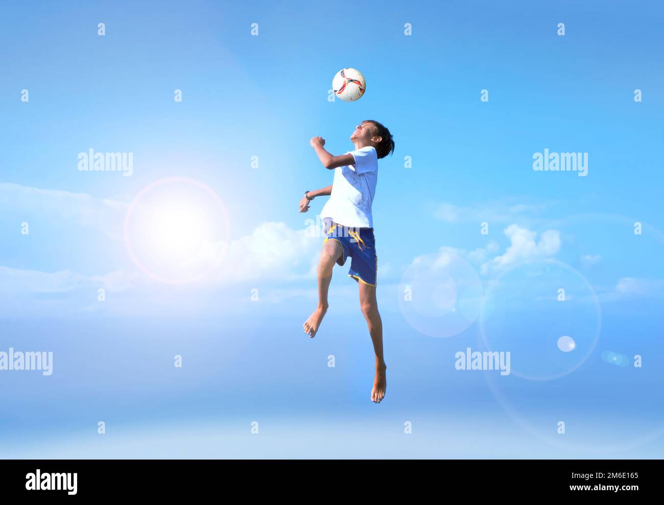 Young boy in a jump, football player doing amazing makes a headbutt a background of blue sky Stock Photo