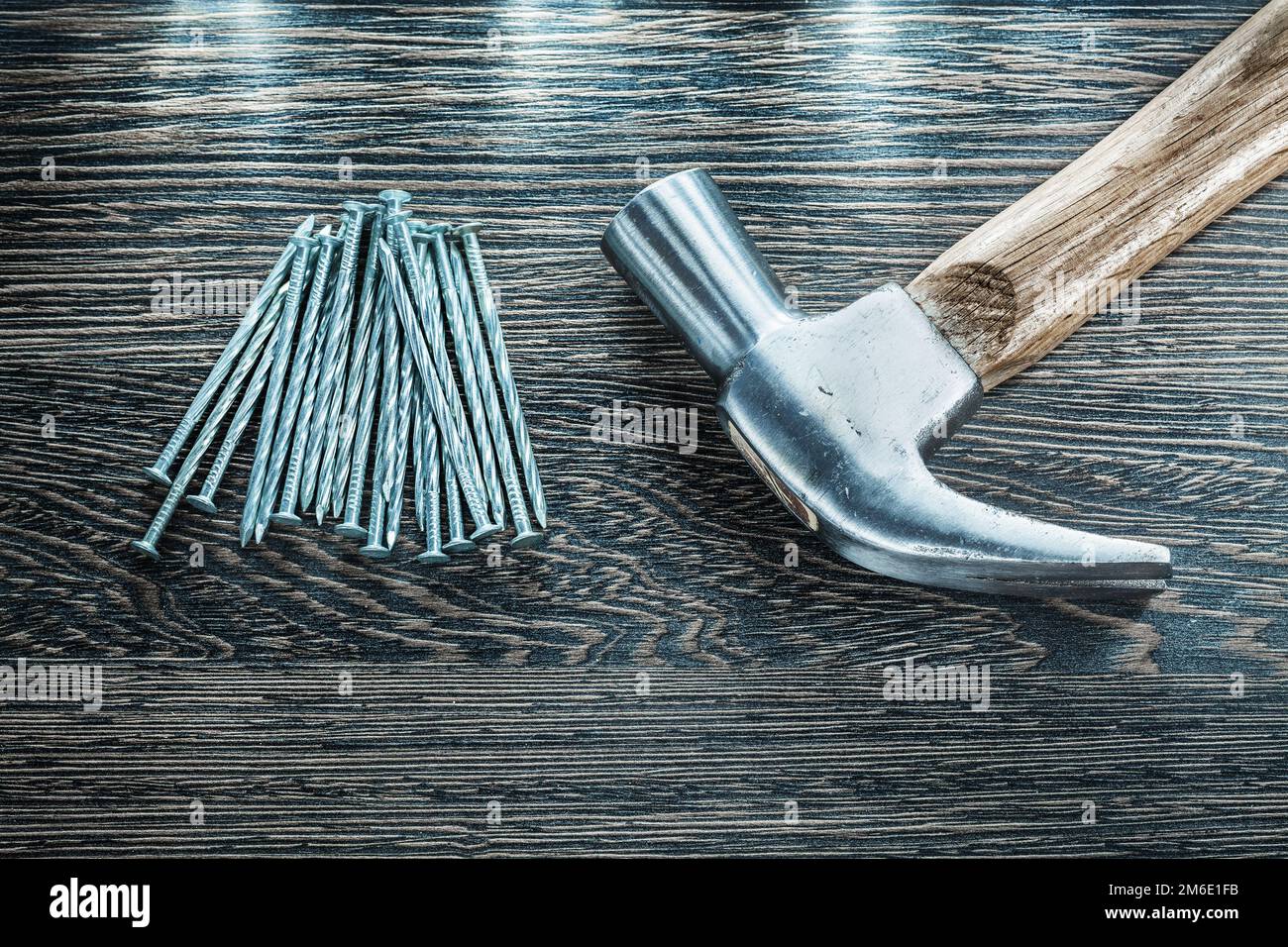 Construction nails claw hammer on wooden board. Stock Photo