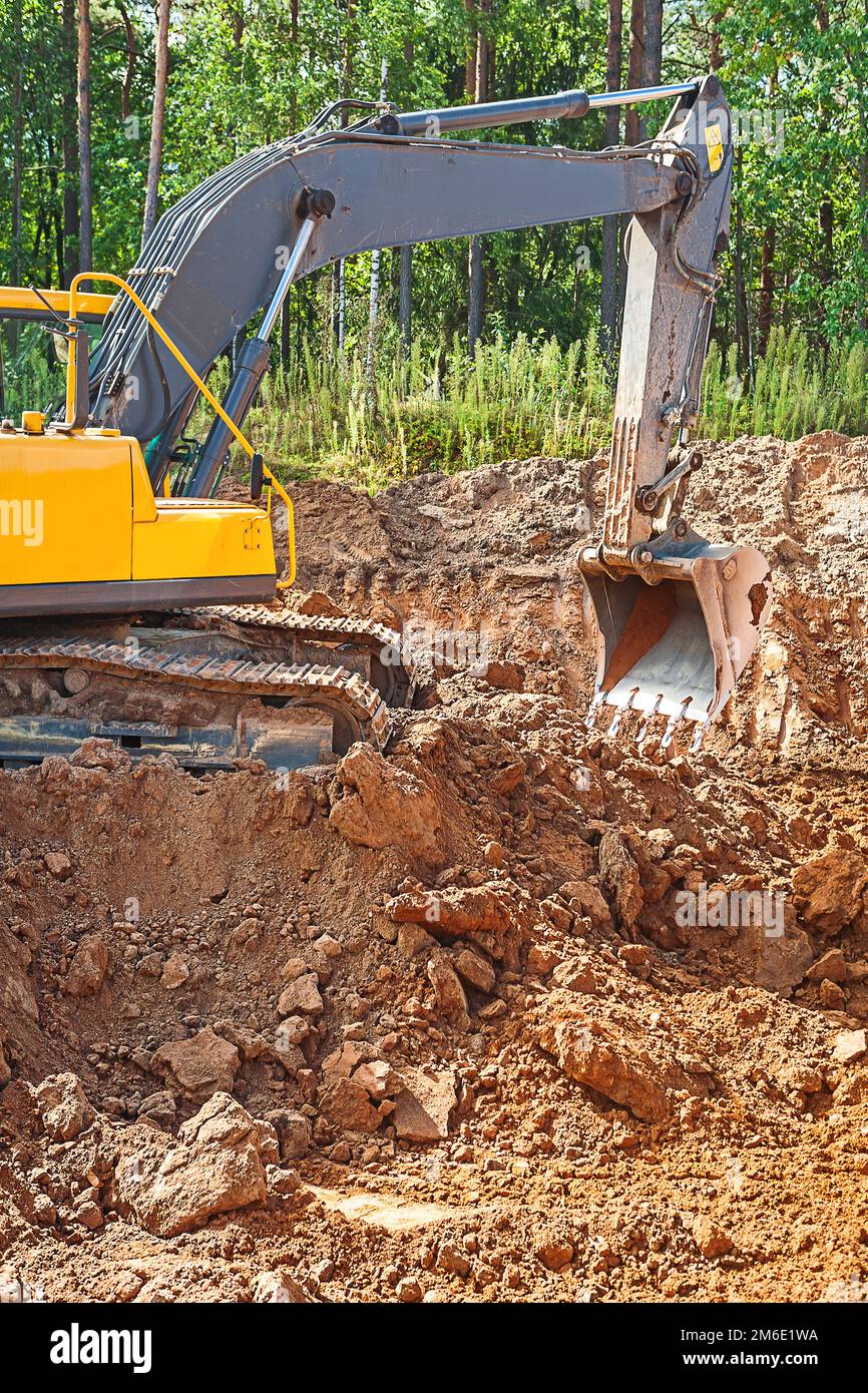 exkavator digging clay ground on construction site in forest Stock Photo