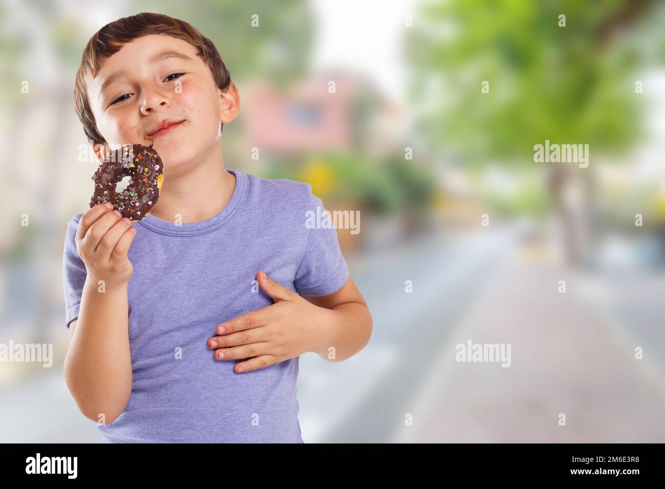 Young boy child eating donut town copyspace copy space unhealthy sweet sweets Stock Photo