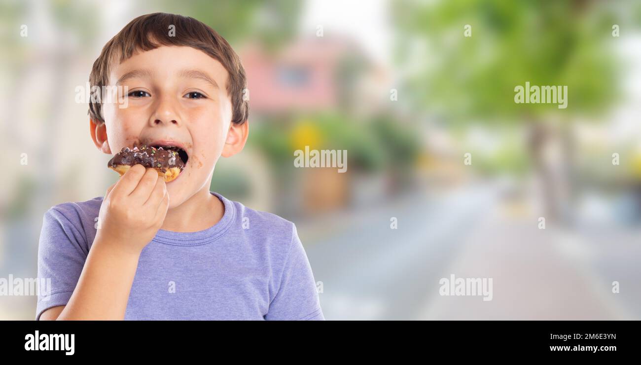 Little boy child eating donut town banner copyspace unhealthy sweet sweets Stock Photo