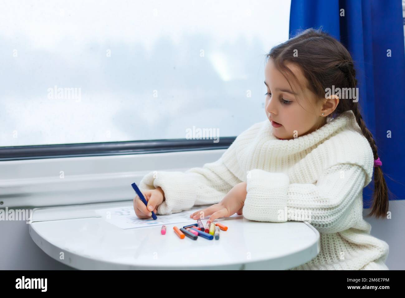 The girl sitting at a desk writing in train Stock Photo - Alamy