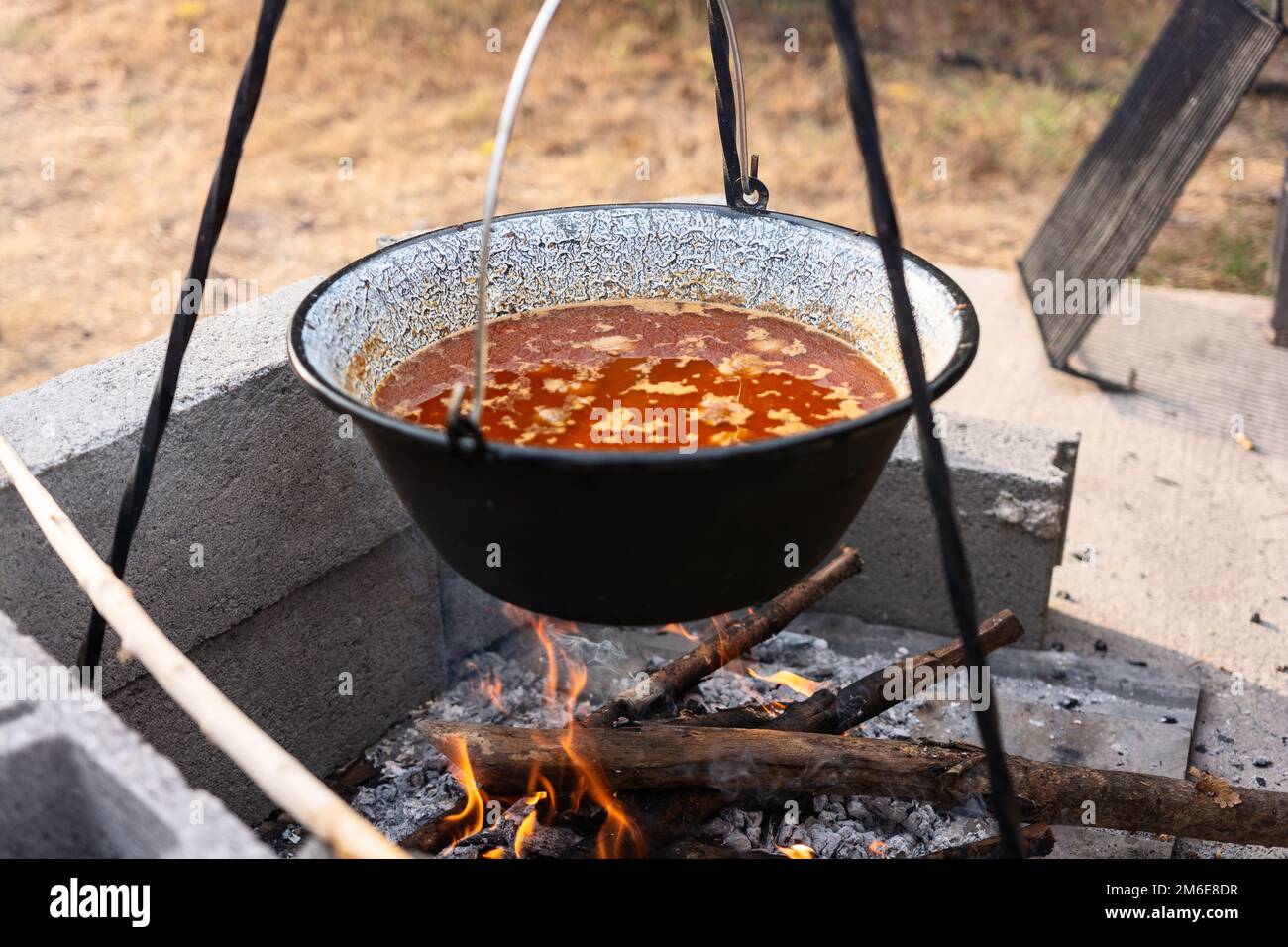 Cooking pot with soup stand in camping fire and getting prepared for