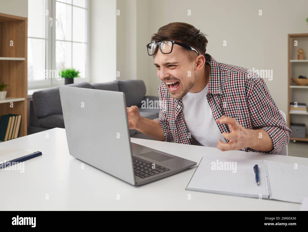 Young man frustrated because of error and data loss shouting at his laptop computer Stock Photo