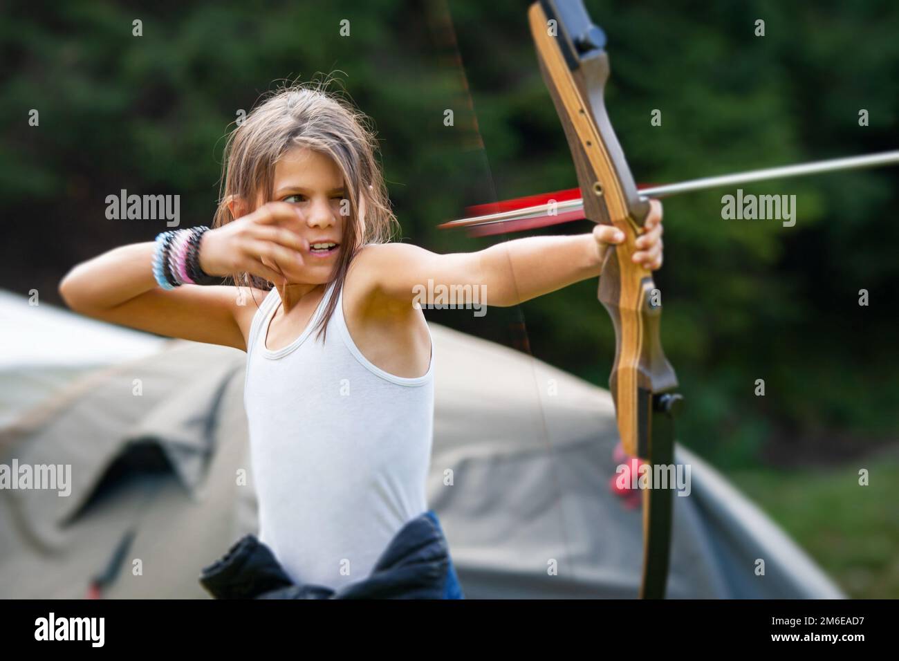 Gipsy girl enjoying with the arrow leaving the bow in a glade camp Stock Photo