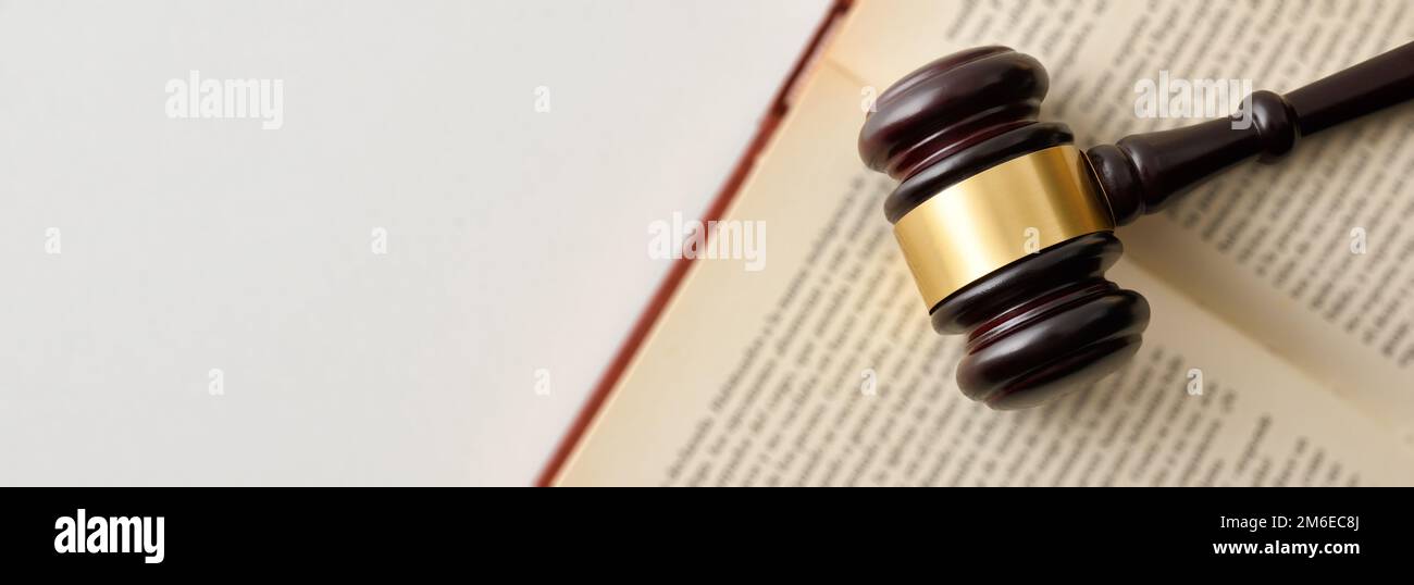Background detail with gavel on open law book isolated on white table. Top view Stock Photo