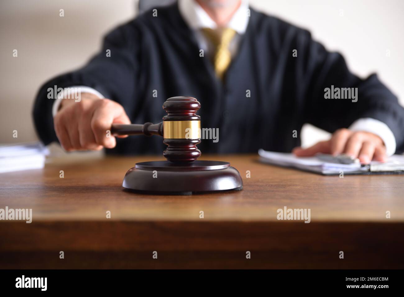 Detail of a judge passing sentence by hitting with the gavel on a wooden table closeup. Front view Stock Photo