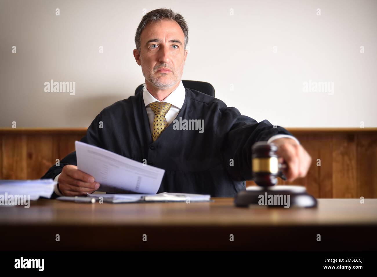 Detail of a judge passing sentence by hitting with the gavel on a wooden table. Front view Stock Photo
