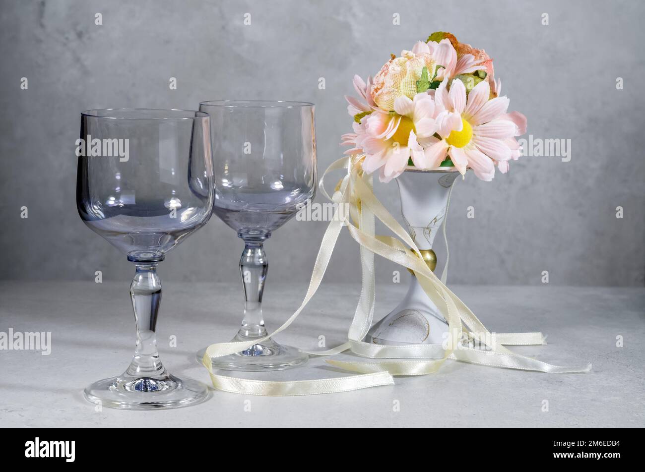 two empty glasses,a bouquet of flowers in a vase on a gray marbled background,decoration,artwork,frame design,wedding invitation,poster,product packag Stock Photo