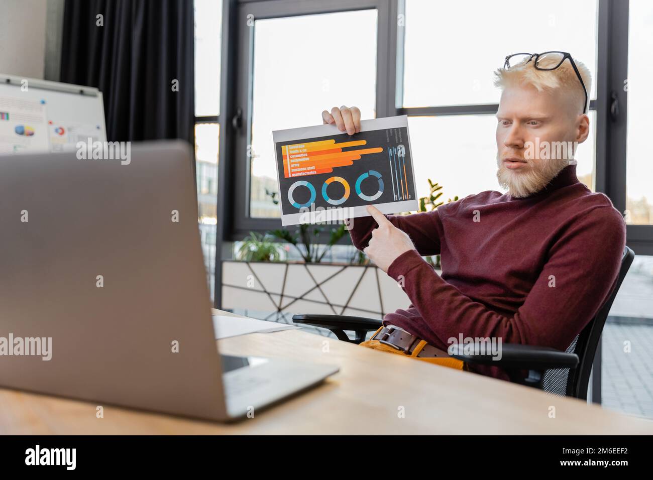 bearded albino businessman in glasses pointing at infographics during video call on laptop,stock image Stock Photo