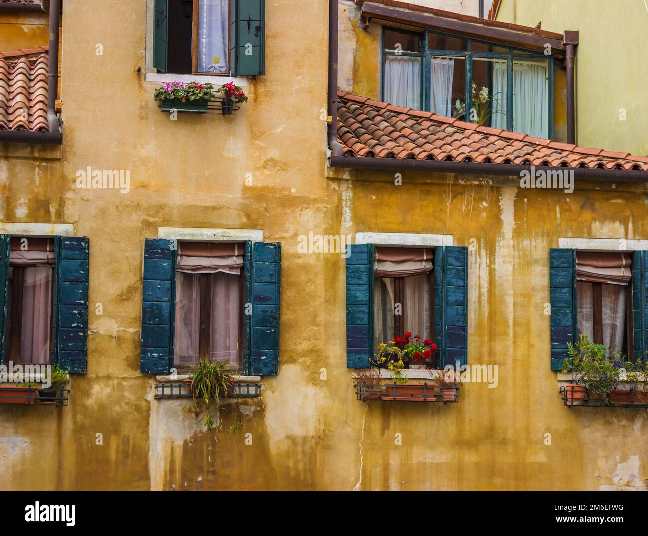 Vintage window on yellow cement wall. Old town in Venice. Stained glass window of a house near the canal in Venice, Italy. Stock Photo