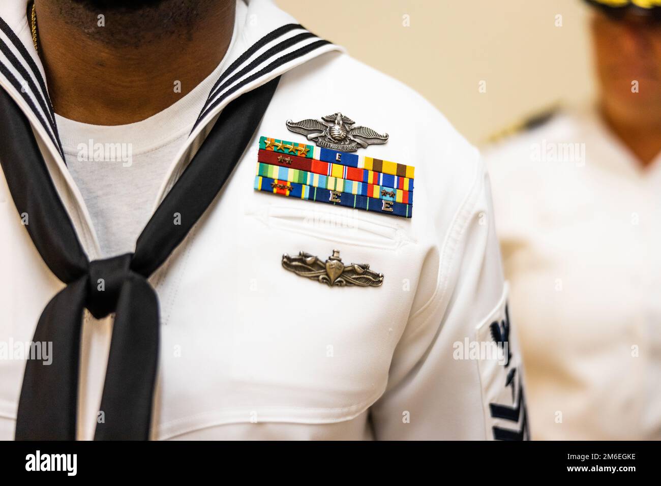 Ribbons and medals are displayed on the dress white uniform of a U.S. Navy Sailor with 21st