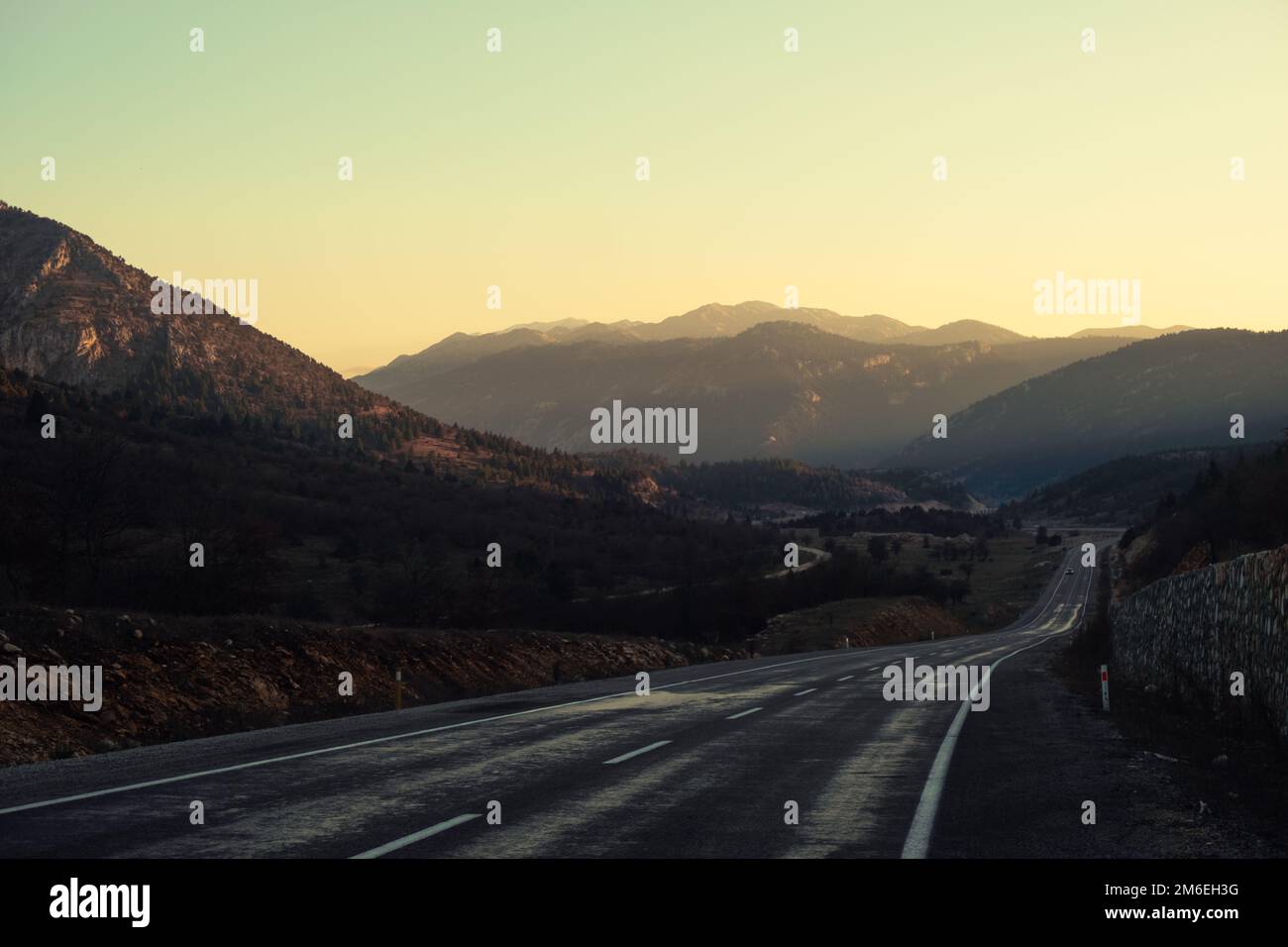Asphalt road among mountains at sunset Stock Photo - Alamy
