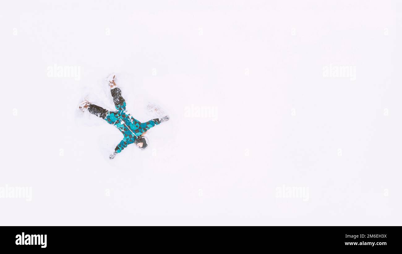 Happy girl lying on snow and making snow angel figure Stock Photo Alamy