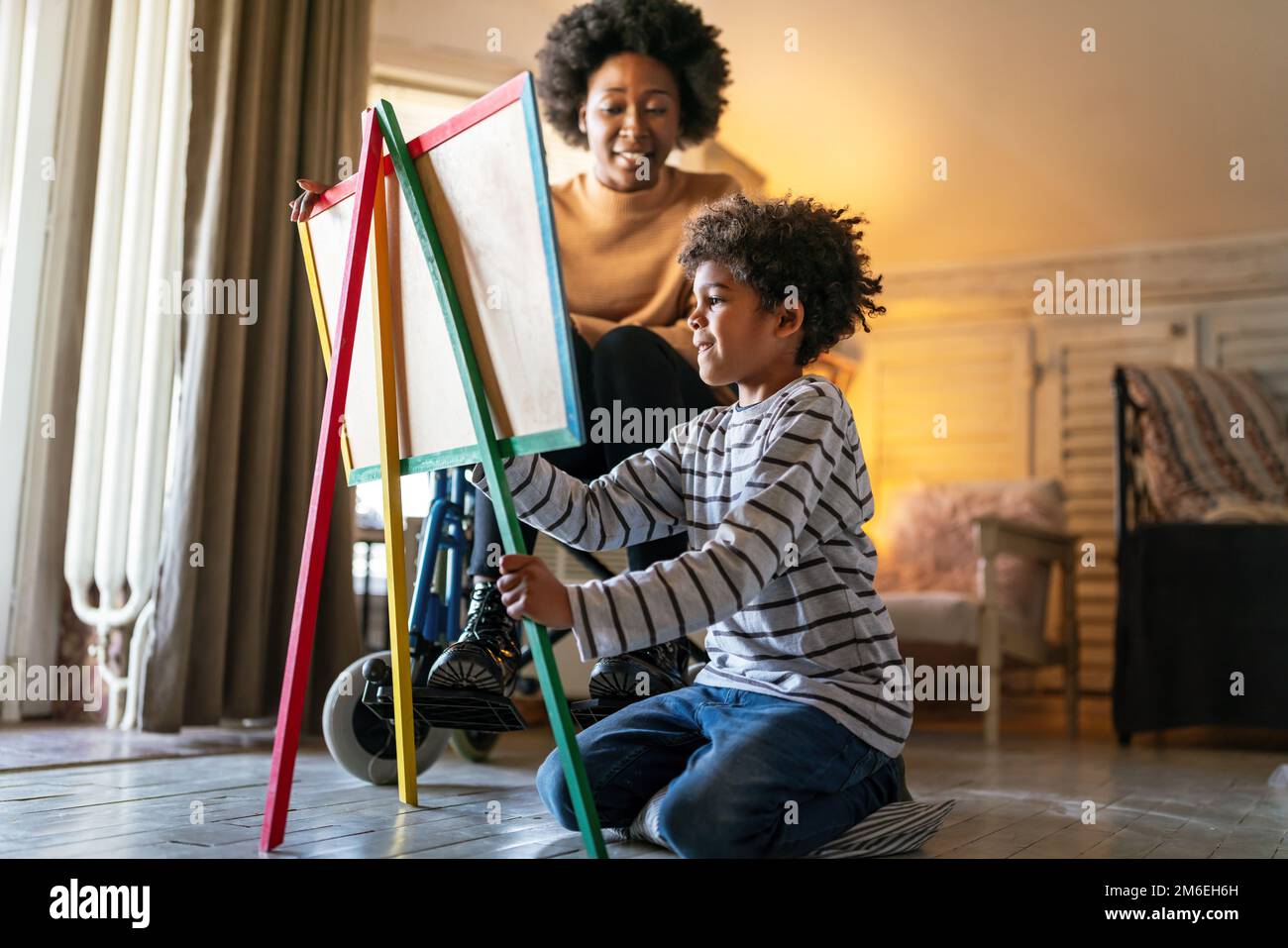 Happy black woman play and learning with little kid at home. Education children development concept Stock Photo
